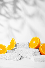 Wall Mural - Beauty skin care product presentation podium and display made with porous stones and oranges on white sunny background. Studio photography.