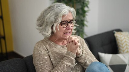 Poster - Middle age woman with grey hair stressed sitting on sofa at home