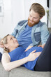 © auremar - happy man with pregnant woman at home on couch