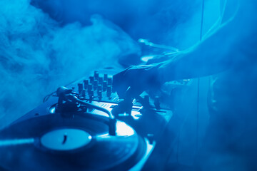 Wall Mural - Silhouette of a club DJ mixing music in smoke on stage. Professional disc jokey plays set on techno party