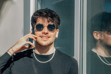 Wall Mural - young man in sunglasses talking on mobile phone in summer on the street