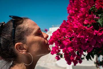 Woman smellingb eatutiful purple flowers (Lagerstroemia shrub) on greek island Santorini