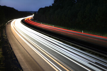 white and red traces of light from moving cars on highway at night six lines autobahn car road long exposure shot fast moving cars