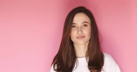 Wall Mural - Playful happy contented brunette woman blinking eye, looking at camera with toothy smile, winking and flirting, expressing optimism. Indoor studio shot isolated on pink background.