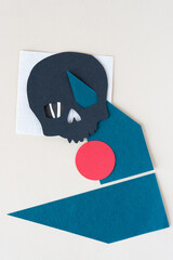 Sticker - cut paper shapes and black paper skull on a light background