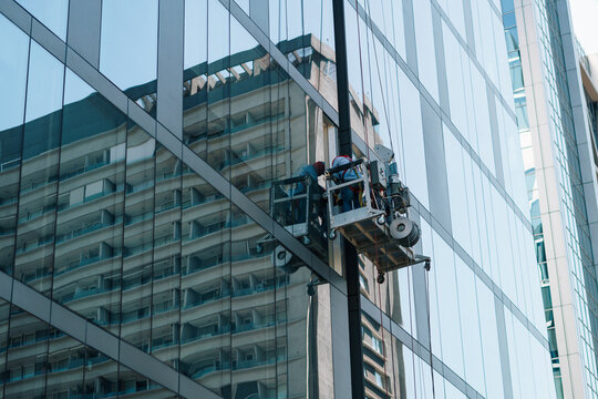 trabajador en alturas limpiando vidrios en un edificio en el centro en una grúa mecánica con cuerdas