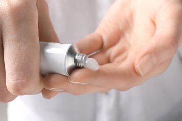 Woman squeezing out ointment from tube on her finger, closeup