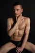 © vladorlov - Adult attractive man with a beautiful body posing in the studio. Black background.