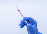 Fototapeta  - szczepionka - strzykawka trzymana w dłoni w niebieskiej rękawiczce na białym tle