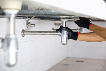 Wall Mural - Technician plumber using a wrench to repair a water pipe under the sink. Concept of maintenance, fix water plumbing leaks, replace the kitchen sink drain, cleaning clogged pipes is dirty or rusty.