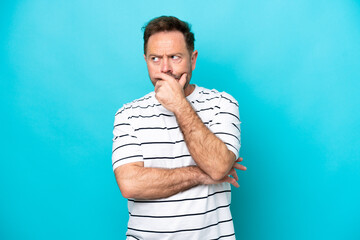 Wall Mural - Middle age caucasian man isolated on blue background having doubts and with confuse face expression