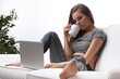 © Giulio_Fornasar - Confident woman on couch with warm drink and laptop, barefoot an