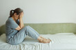 © evafesenuk - Senior woman sitting on sofa covering her face with her hands, suffering from depression.