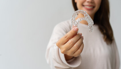 close up woman hand holding dental aligner retainer (invisible) on background for beautiful teeth and dental treatment course concept