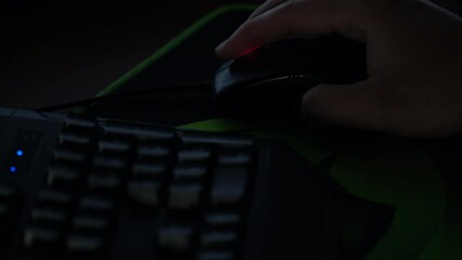 A man browses a website with a mouse in front of a computer in a dark room
