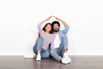 Multiracial couple sitting on floor against white wall