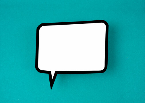 The White speech bubble shaped post it note on green background with copy space.