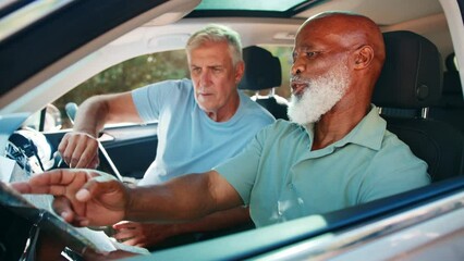 Wall Mural - View through passenger window of two senior male friends with map on journey in car together, lost and arguing over directions - shot in slow motion