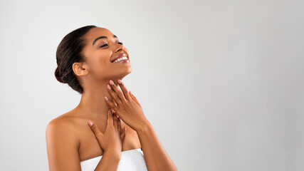 Wall Mural - Joyful black woman touching her soft flawless skin on neck