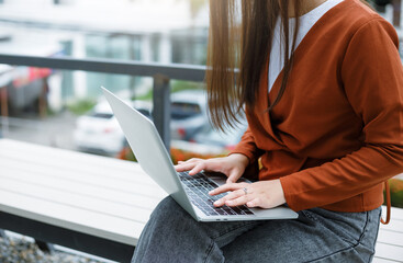 Wall Mural - Young asian woman sitting on bench outdoor use laptop pc computer work online, People urban lifestyle concept.