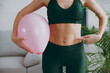 © ViDi Studio - Cropped close up young strong sporty athletic fitness trainer instructor woman wear green tracksuit train hold balloon point on belly do exercises at home gym indoor. Workout sport motivation concept.