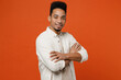 Side view smiling happy fun young man of African American ethnicity wear light shirt casual clothes hold hands crossed folded look camera isolated on orange red background studio. Lifestyle concept.