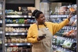 © Seventyfour - Waist up portrait of smiling black woman working in supermarket and wearing apron, copy space