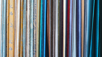 Poster - Mix colorful hanging vertical stripe textile, fabrics, cloths on the rack. Texture of multicolored fabrics close up.