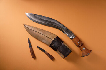 Ancient curved kukri knife on an orange background, scabbard, top view