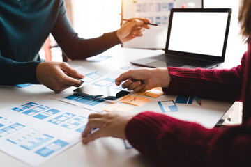Close up ux developer and ui designer brainstorming about mobile app interface wireframe design at modern office. Creative digital development agency