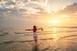© Kittiphan - Young woman traveler relaxing and enjoying the beautiful sunset on the tranquil beach, Travel on the summer vacation concept