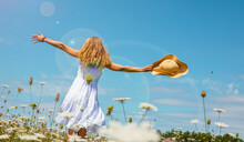Woman wearing white dress dancing in a field with flowers and blue sky- freedom,  active,  healthy concept