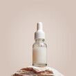 Glass dropper bottle with white liquid essence, serum, cream on stand from natural stone, minimal beige gradient background. Natural Cosmetic, monochrome aesthetic mockup cosmetic product