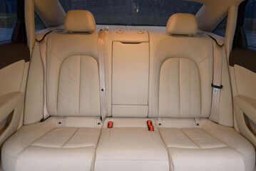 New car inside. Beige back seats in a sedan. Car cleaning theme. Luxury car rear leather seats row. Interior of new modern clean expensive car. Passenger seats with nappa leather. Closeup details.