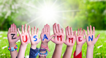 Wall Mural - Children Hands Building Word Zusammen Means Together, Grass Meadow