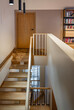 © Andrew Mayovskyy - Apartment entrance hall with wooden staircase access to upper floor, shelves with books. Modern stairway inside in modern house interior.