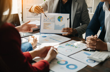 Business documents on office table with smart phone and calculator digital tablet and graph business with social network diagram and two colleagues discussing data working in the office.