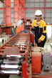© Nassorn - Latin woman engineer inspecting heavy machinery system in production line for manufacturing safety. Female technician doing repair service. Maintenance machine equipment in metalwork factory concept.