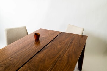 Wooden table, two chairs and a cup, placed on the table against a white background