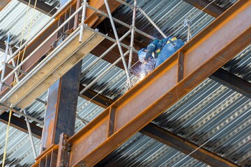 Wall Mural - Male welding steel on a girder at heights, on a building structure in Mexico Guadalajara