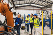 © Westend61 - Engineer with colleagues having discussion over robotic arm