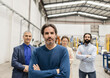 © Westend61 - Mature engineer standing with arms crossed in front of colleagues at factory