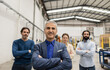 © Westend61 - Smiling businessman standing with arms crossed in front of colleagues at factory