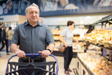  man and a woman are walking around the supermarket, looking at the products