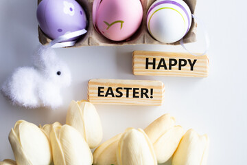 Colorful decorative eggs and HAPPY EASTER text close-up, against the background of a white rabbit