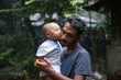 © Susmit - South asian young rural father holding his little son, village baby boy playing with his young dad, lovely family moments in outdoor
