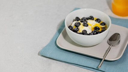 Wall Mural - Healthy Greek yogurt with fresh blueberry and honey in white bowl on light grey marble background with copy space. Morning still life with healthy food. Healthy breakfast