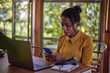 © kerkezz - A young woman sitting in front of a laptop and typing a message on the phone.