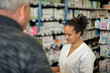 © AUFORT Jérome - young woman pharmacist helping a senior at work