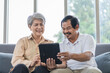 © SKW - Asian couple, elderly man and woman sitting on the sofa having fun chatting together at home. Concept: health insurance, life insurance, retirement happiness.